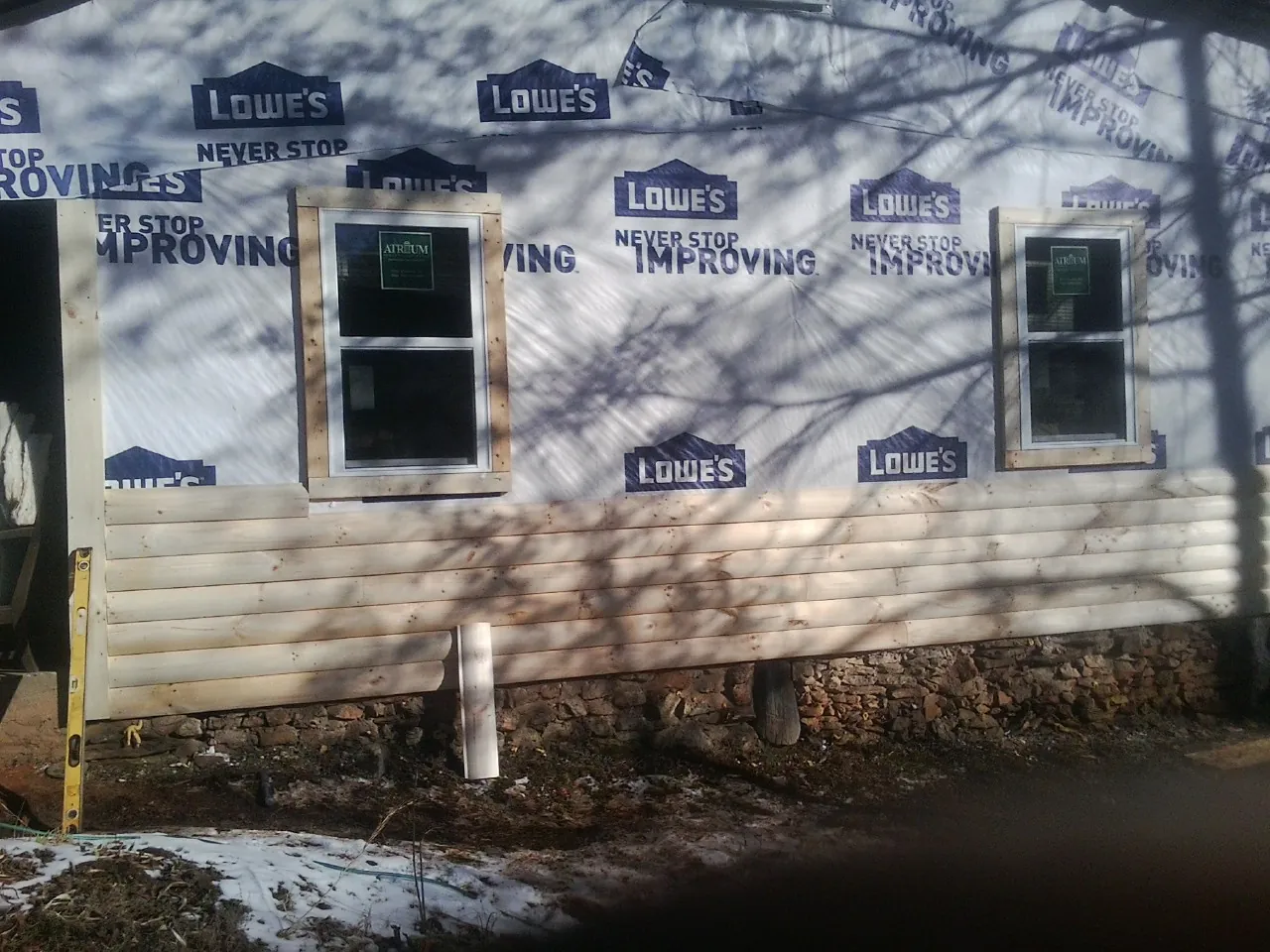 House wrap and new log siding going up on an exterior wall in Mantador
