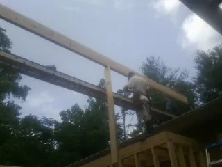 Carpenter setting a ridge beam over a new addition frame — Ice Dam Removal by Roofing Brothers in Mantador