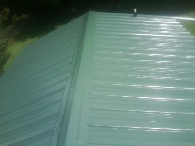 New green metal panels meeting at the ridge of a roof — Flat Roof Repair work by our crew in Mantador