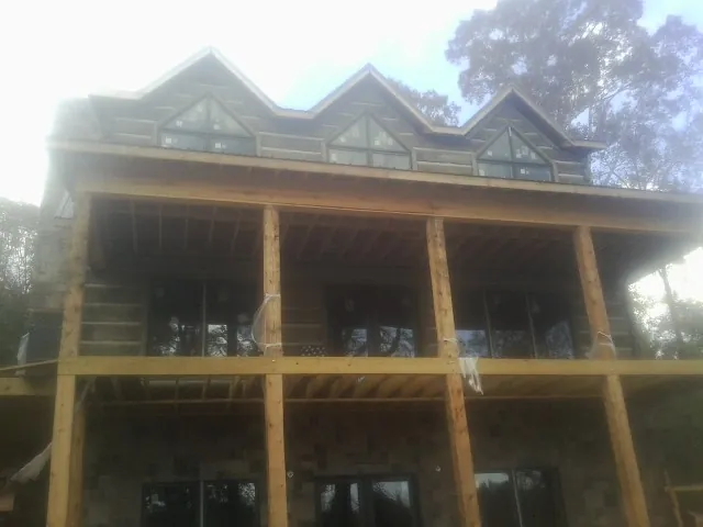 Dormers and porch framing on a large log home under construction — Roof Coating work by our crew in Mantador