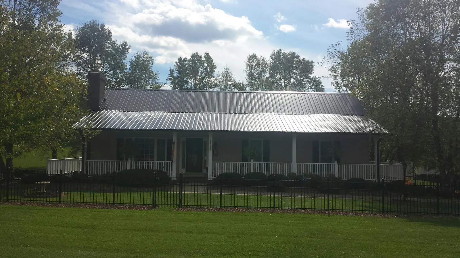 Gray metal roof on a brick ranch with a full width front porch — Gutter Guard Installation work by our crew in Mantador