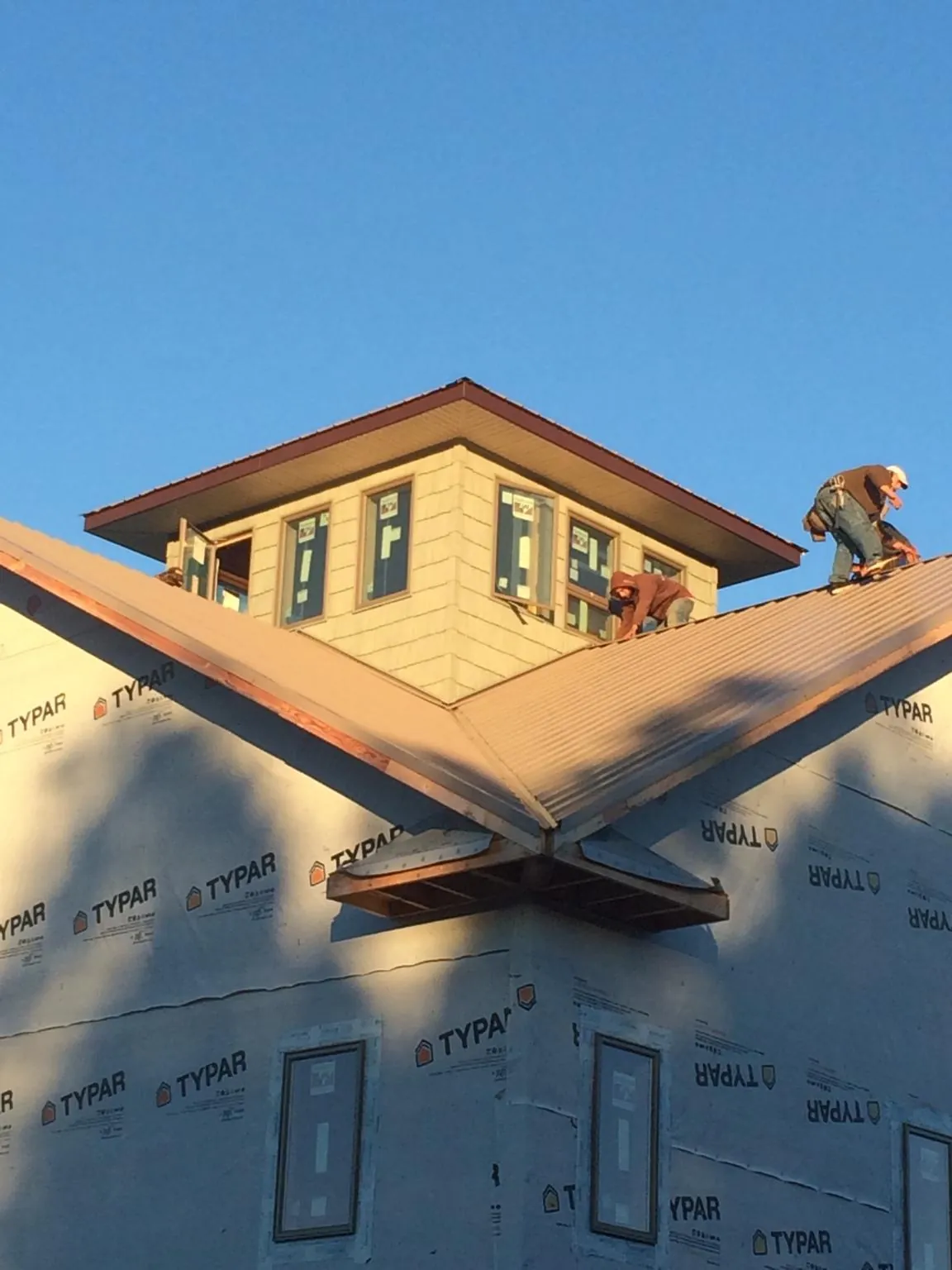 Roofers working around a rooftop cupola on a new metal roof at sunset — Roof Waterproofing in Mantador by Roofing Brothers